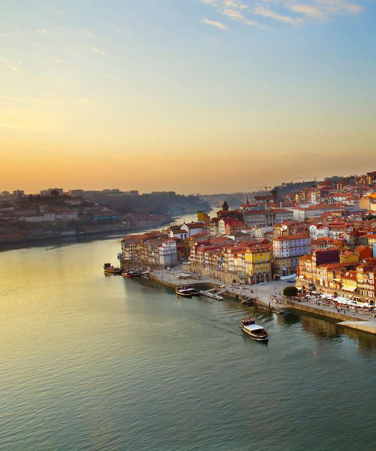 Możesz zobaczyć wzgórze ze starym miastem Porto. Na pierwszym planie widać rzekę.